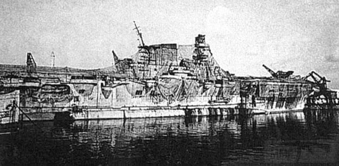 8610 - Work on Aquila was stopped by 1943 and she rusted in Genoa harbour, with a half-hearted attempt to conceal her identity with camouflage nets